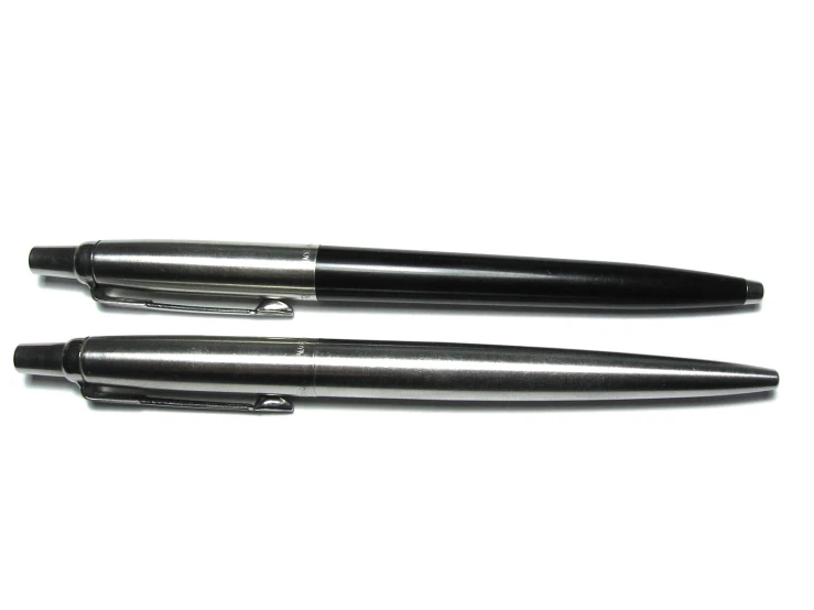 black rollerball pens lined up and open on a white surface