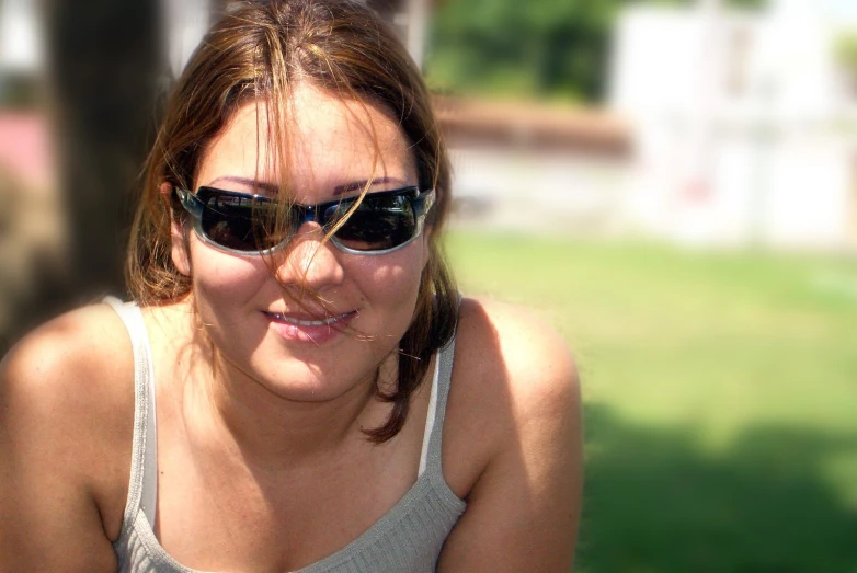 a close up of a person wearing sunglasses sitting on the ground