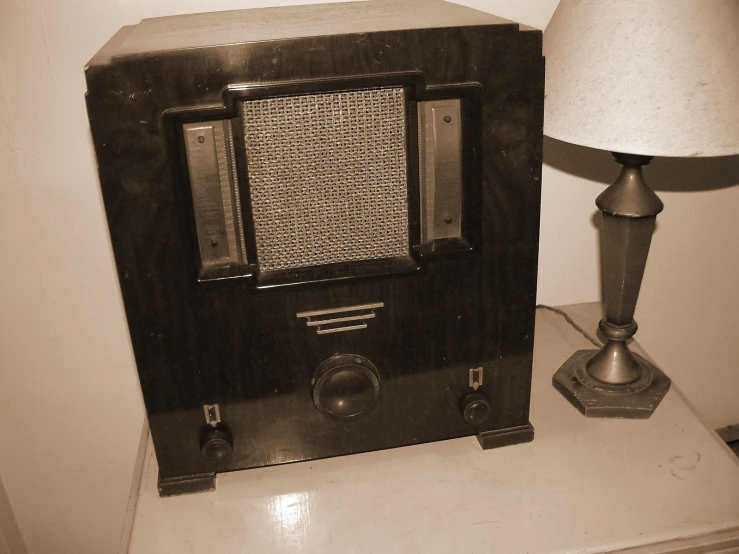 an old fashioned radio next to a lamp on a night stand