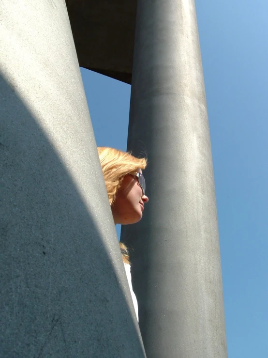 a woman with blonde hair and sunglasses on standing between two poles