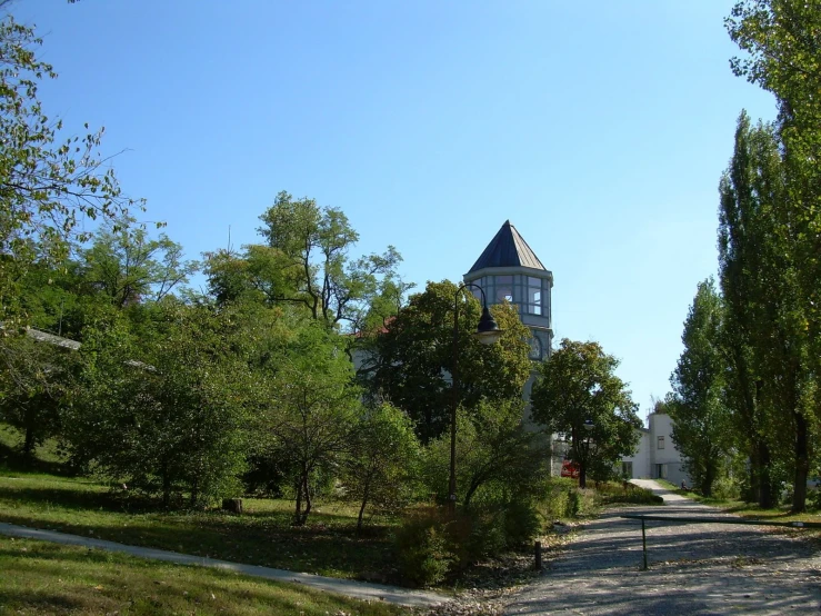 the clock tower is next to a couple of trees and houses