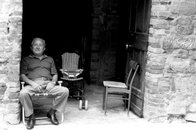 a man sits in a chair outside an open doorway