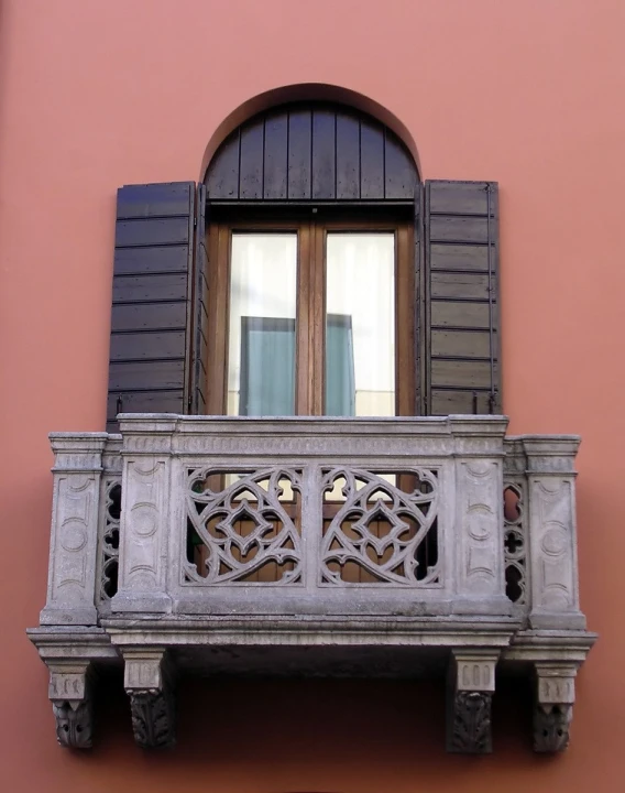the balcony features iron work and wooden windows