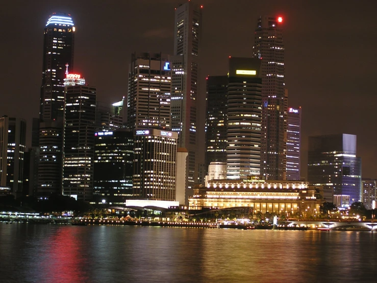 large city with multiple buildings lit up on the side of water