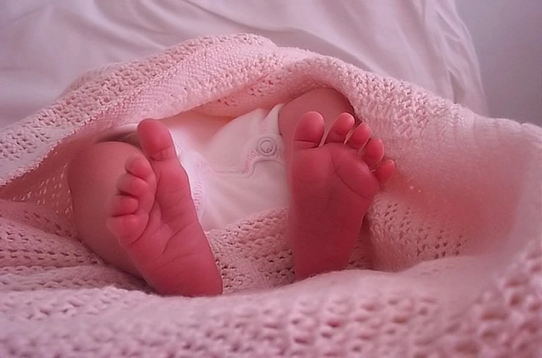 a close up of a baby laying in bed