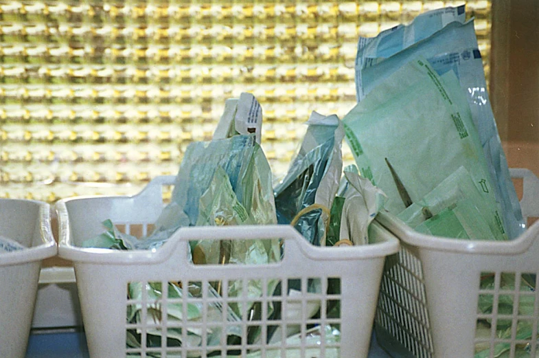 three baskets holding green garbage on top of a counter