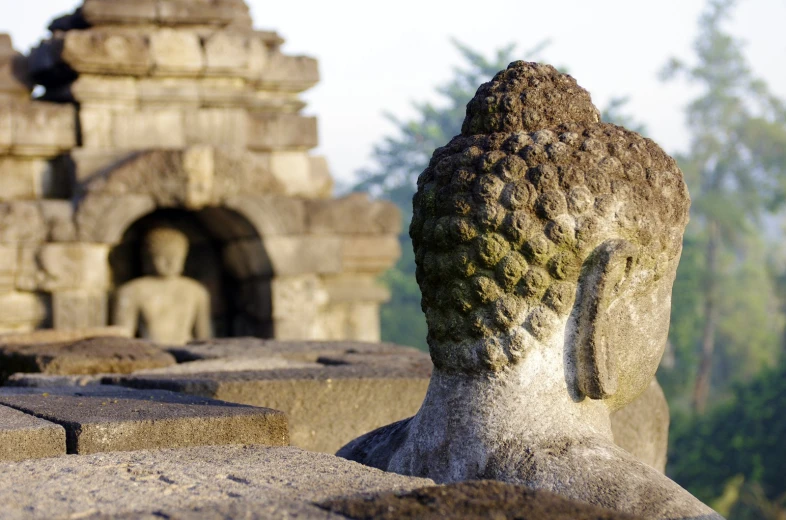 a buddha statue in stone blocks near some ruins