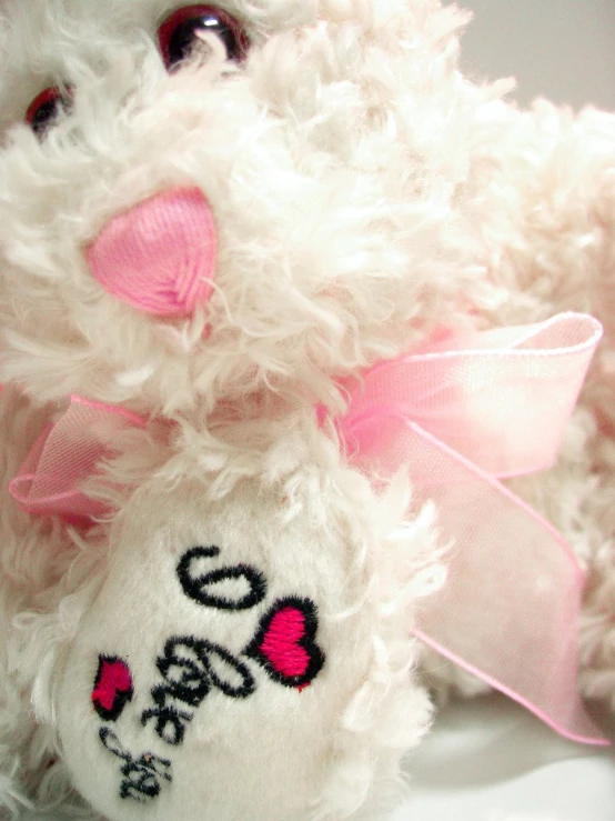 the fuzzy, white teddy bear has a heart painted on it's face