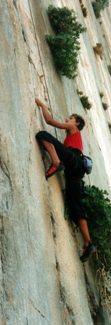 a man with a helmet climbing up the side of a rock