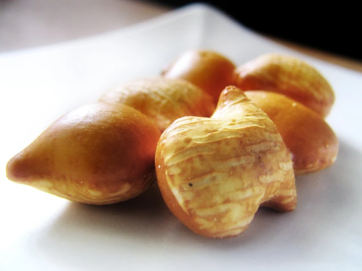 several peeled apricots and their shell on a white plate