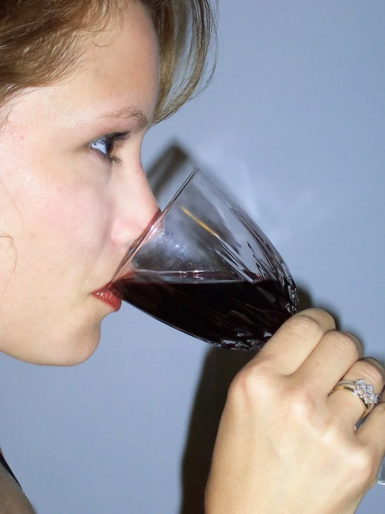 a girl is sipping from a glass of wine