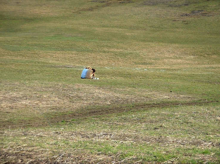 two people laying on the grass in the open field
