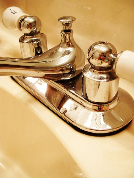 a bathroom faucet with two matching handles and white soap dispenser