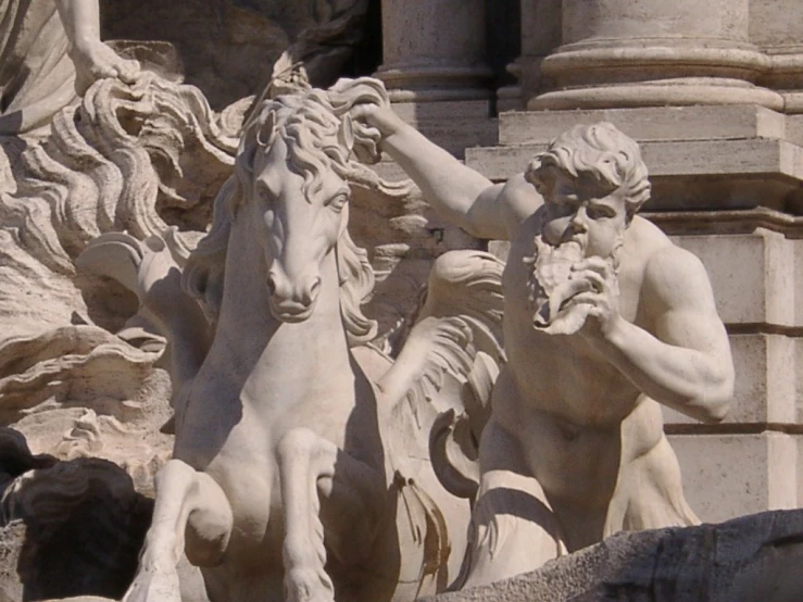 three statues of horses and a man with his hands to their ear