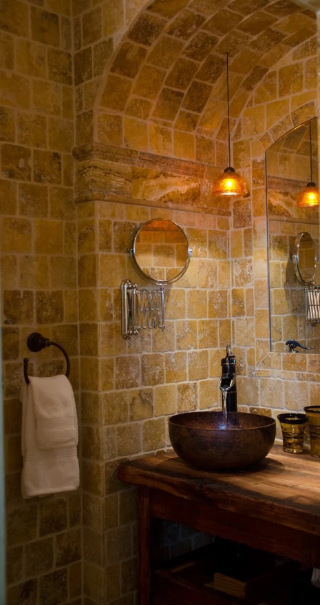 a bathroom with stone walls, two sinks and mirrors