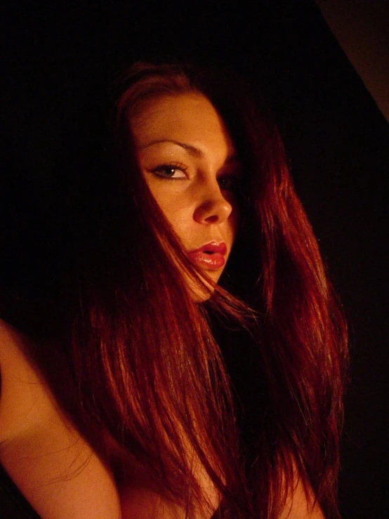 a woman with long red hair and green eyes looks down at the camera