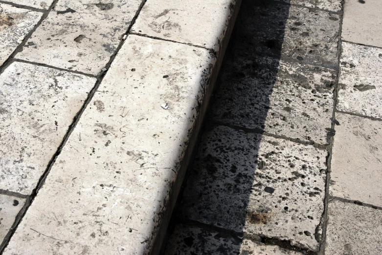 the shadow of a bench on the ground is cast by someone's shadow