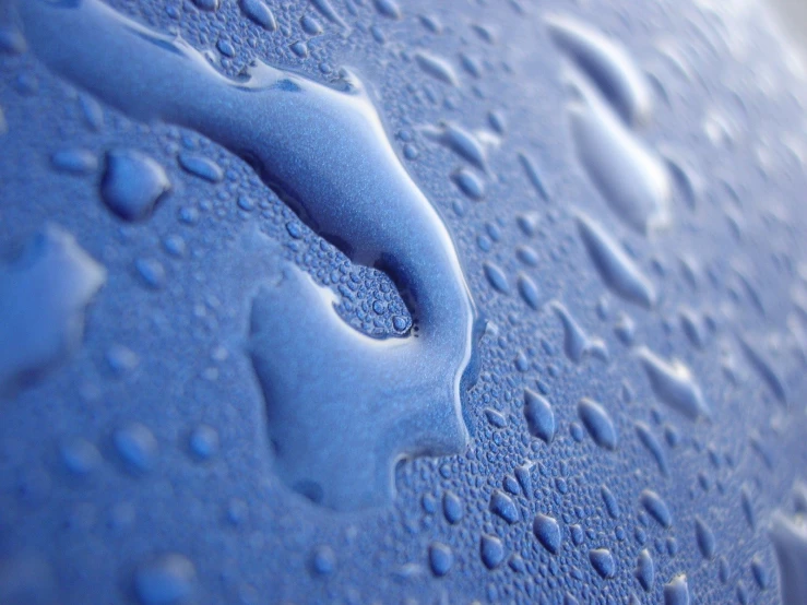 a close up of a blue plastic surface with some water drops