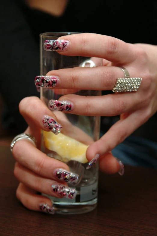 a female is holding a glass filled with lemon and silver polish