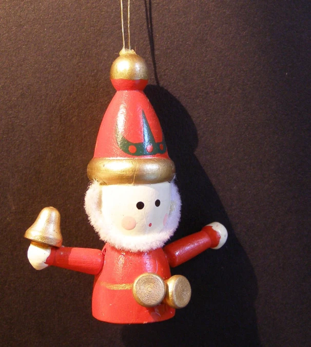 a ceramic santa clause with a bell and a hat