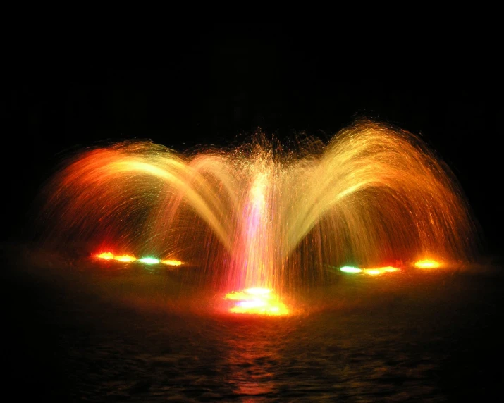 two colorful fountain show lights on the water at night