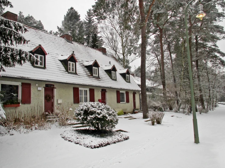 a house with red shutters and white trim is covered in snow