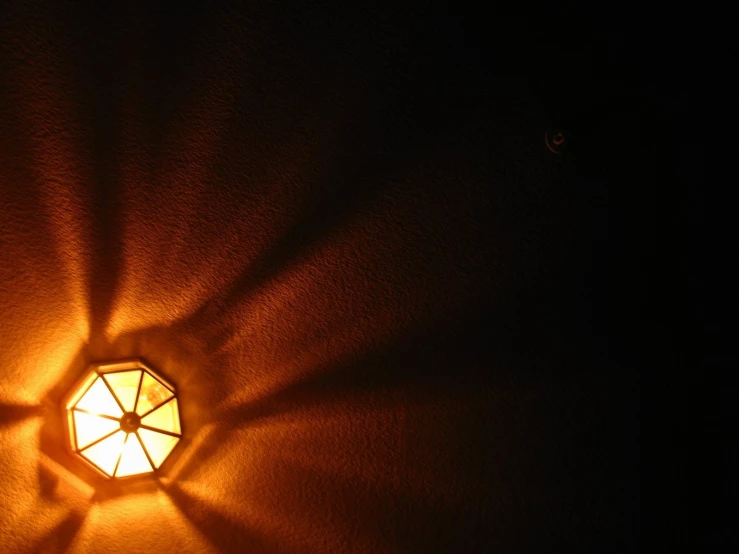 a lit up lamp with an octagonal pattern in a dark room