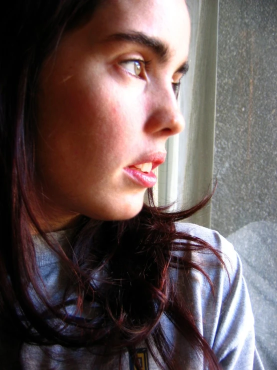 a close up of a young person looking out a window