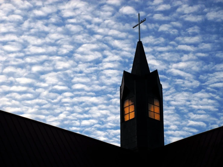 there is a steeple and a cross with sky in background