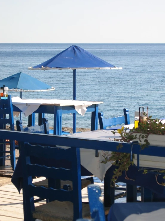 tables with umbrellas set up on a boardwalk overlooking the ocean