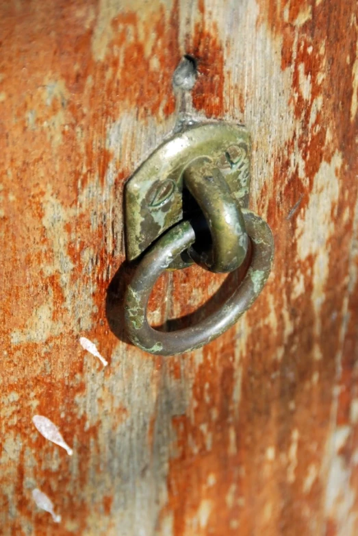 a rusted door knocket with a metal knock latch