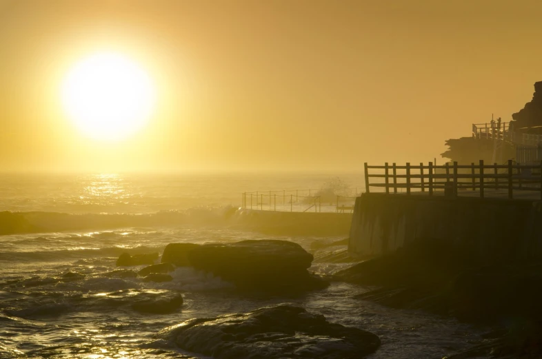 a person is on the shore watching the sun rise over the water