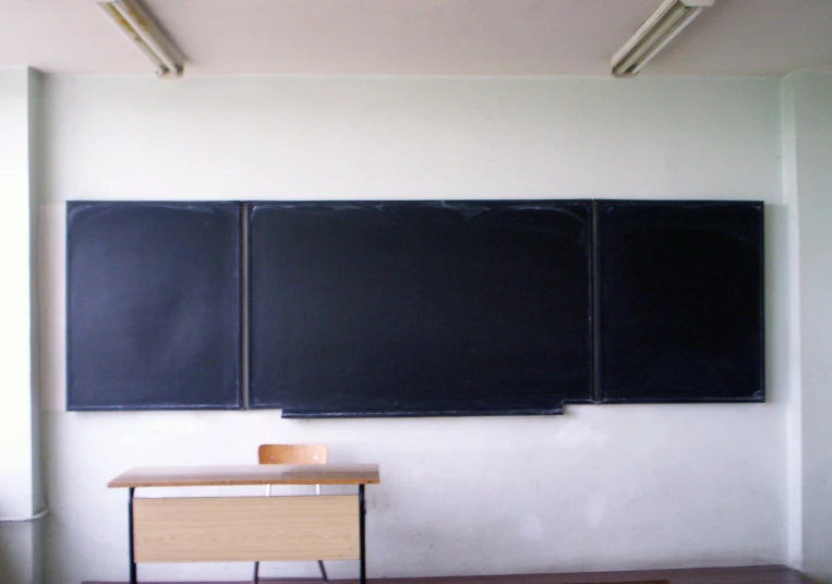 a chalkboard in front of a desk with two blackboards