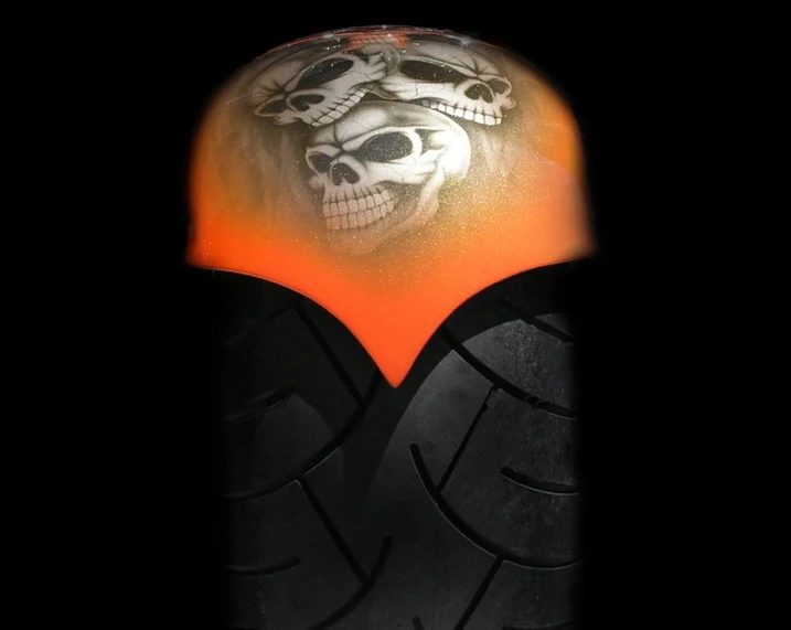 a skull on a motorcycle tire against an orange background
