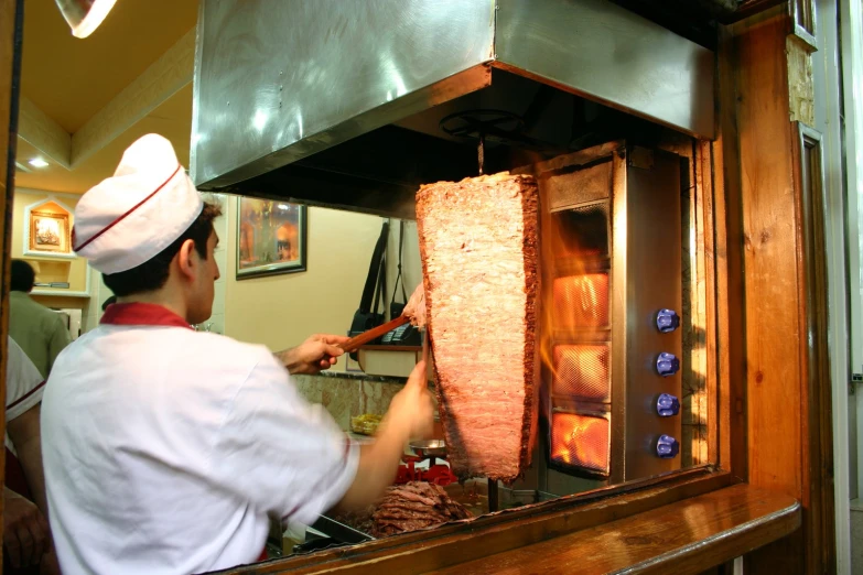 a chef cooking meat on the grill of an oven