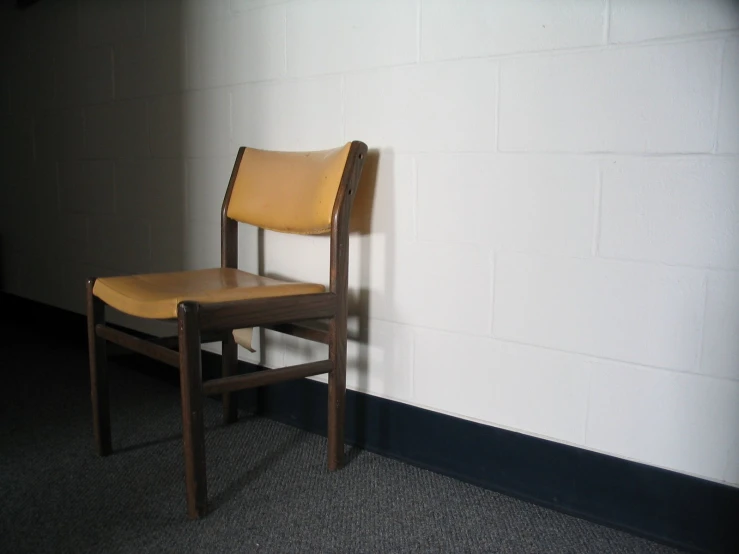 a chair against the wall beside a wall with white paint