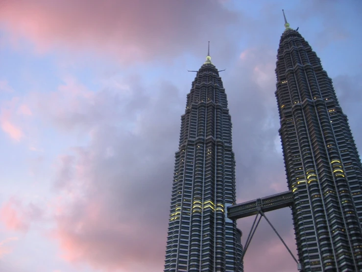 two tall buildings stand against a bright pink sky