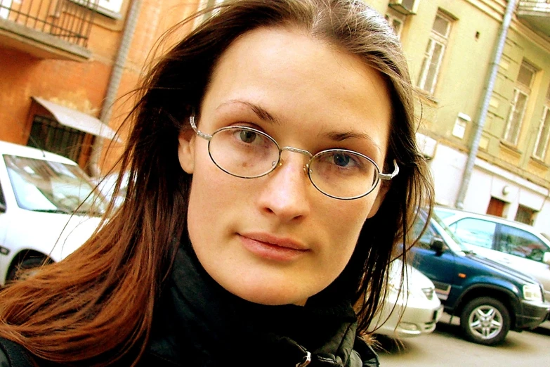 a woman wearing glasses and a black shirt standing in a street