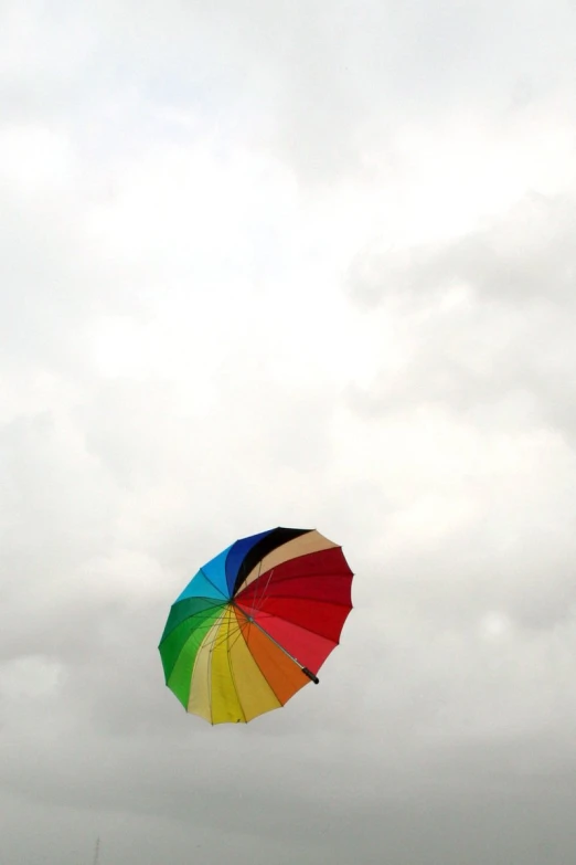 a rainbow umbrella flies high above the beach