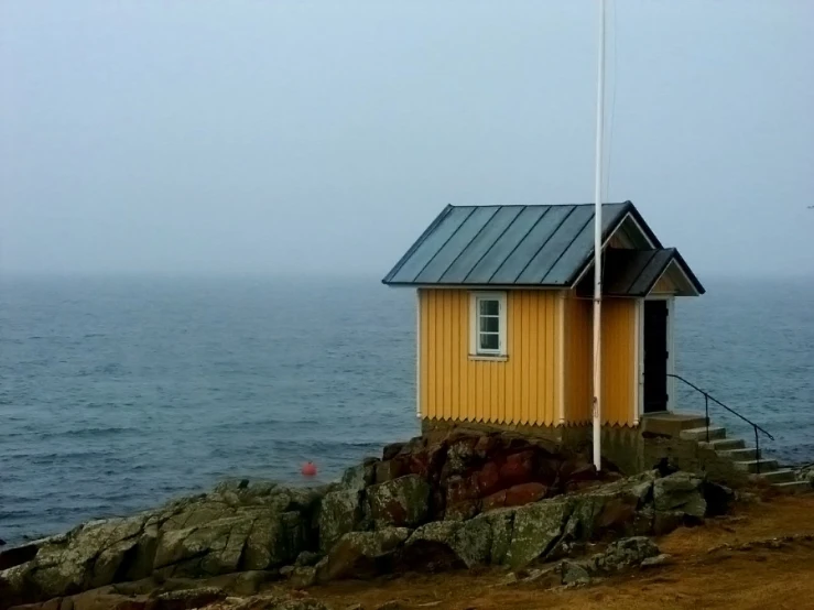 there is a small yellow house on a rocky hill