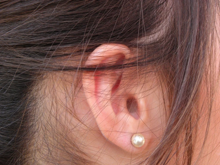 a woman's ear with tiny diamond piercing