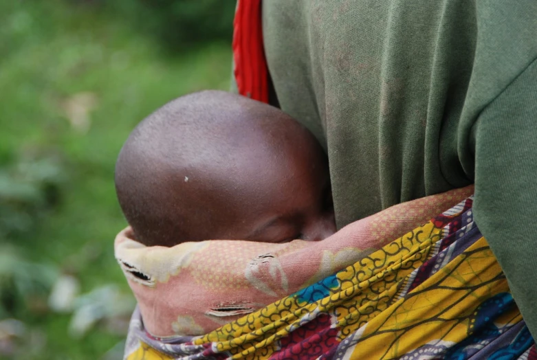 the head of a baby wrapped in a multi - colored scarf