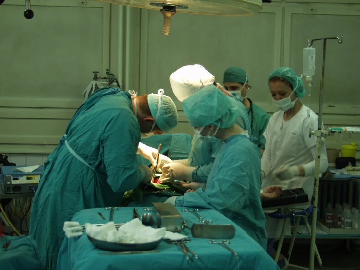 medical personnel doing various tasks on an operating table