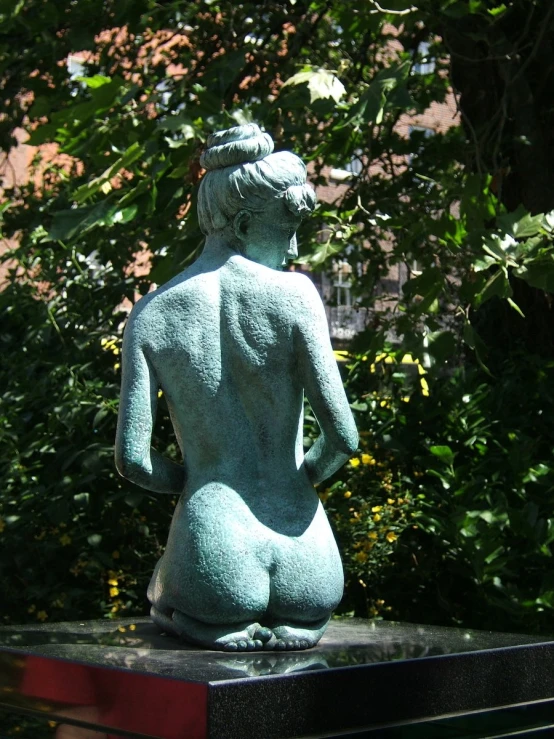 a stone statue sitting on a pedestal in front of trees