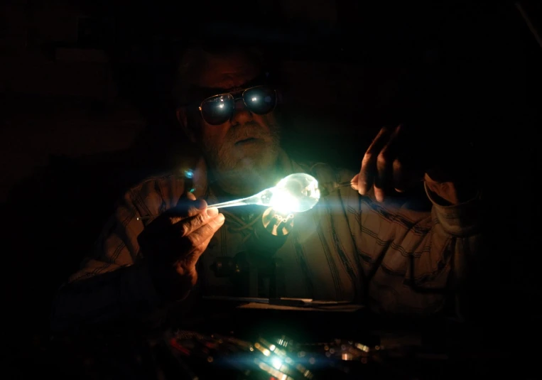 a man with goggles on, holding a glowing green stick