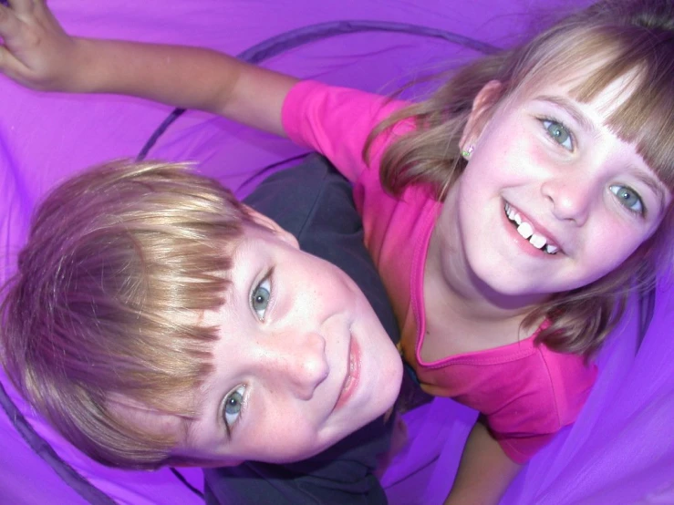 two children are lying down smiling in the blankets