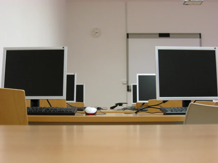 a pair of computer monitors sit on top of a desk