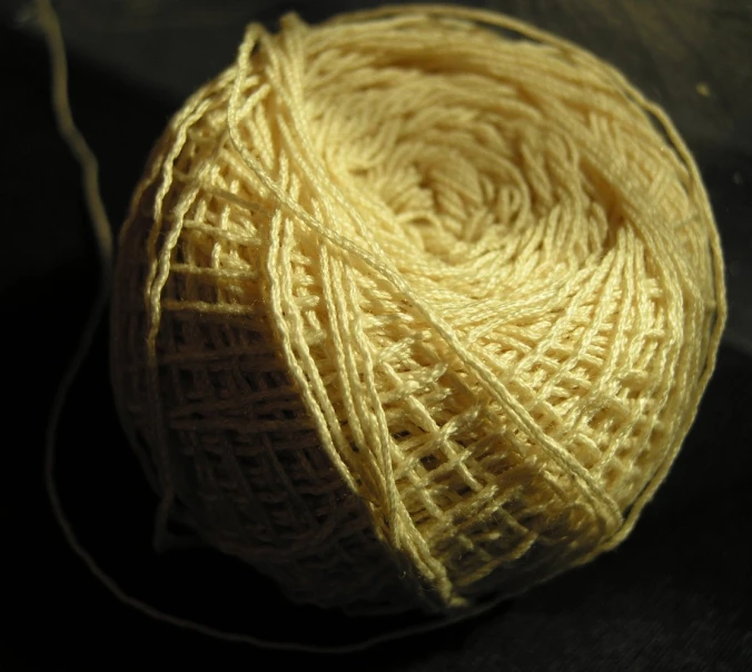 yellow yarn is spooled off and sitting on a black surface