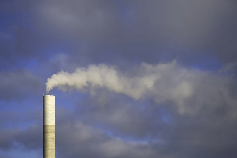 factory smoke coming from tall chimney against a cloudy sky