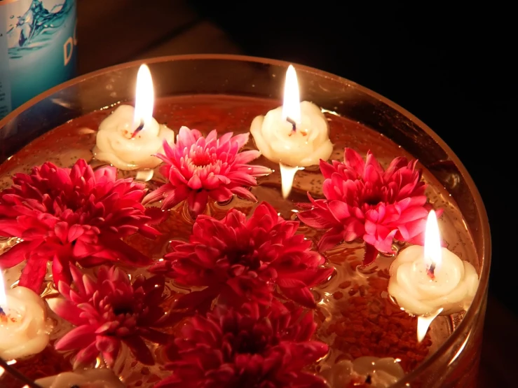 candles with flowers floating in a bowl of water